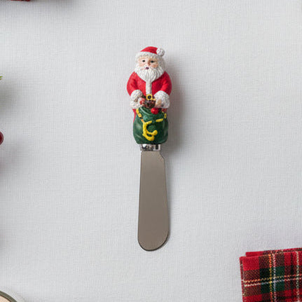 Decorative knife with Santa Claus figure on a white surface with Christmas decorations.
