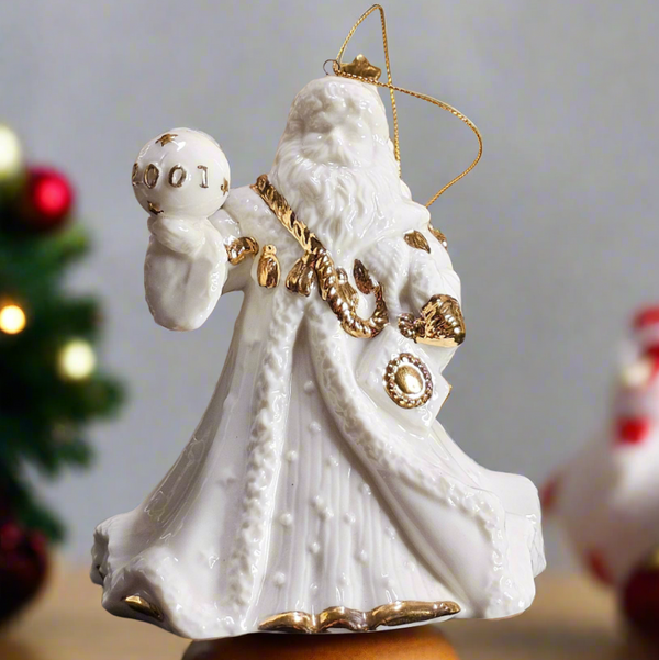 Decorative Christmas ornament of a white figure with gold accents on a wooden base.