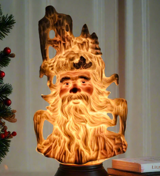 Decorative lamp with a face design on a surface next to books and a Christmas tree.